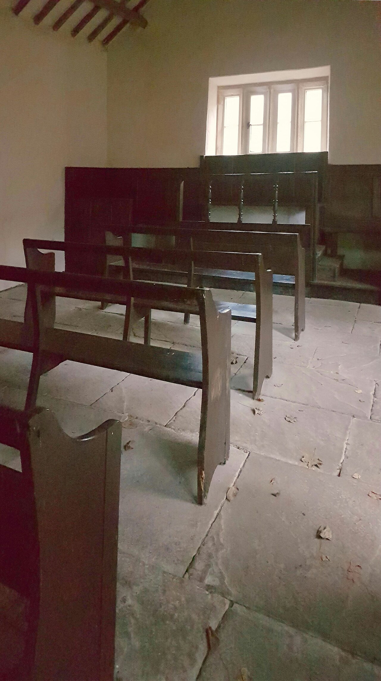 Inside the Farfield Quaker Meeting House: plain wooden benches and bare walls under a small window.