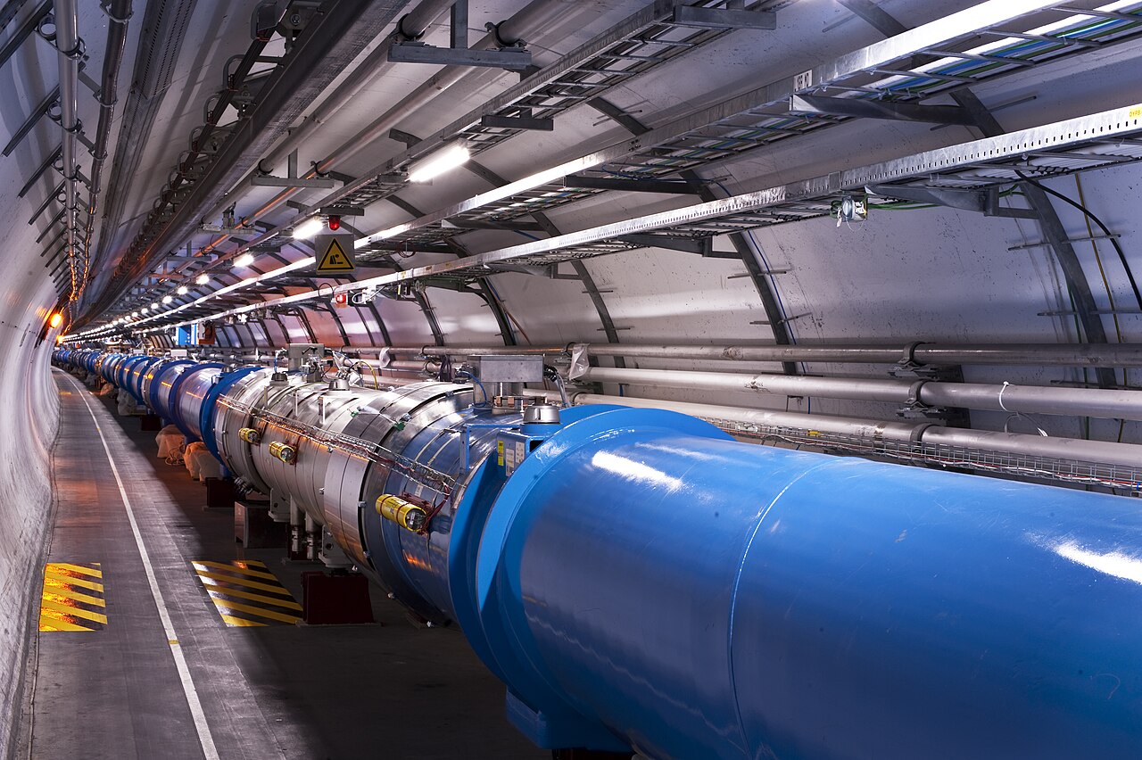 The Large Hadron Collider tunnel at CERN, its blue beamline and dipole magnets curving away under rows of lights.